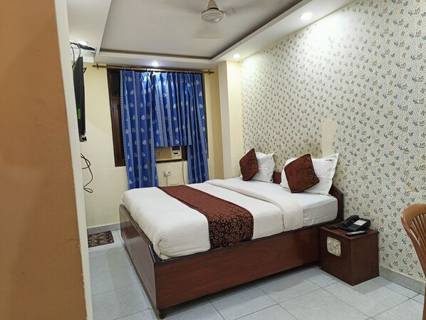 A bedroom with a bed, a bedside table with a phone, and a wall with patterned wallpaper.