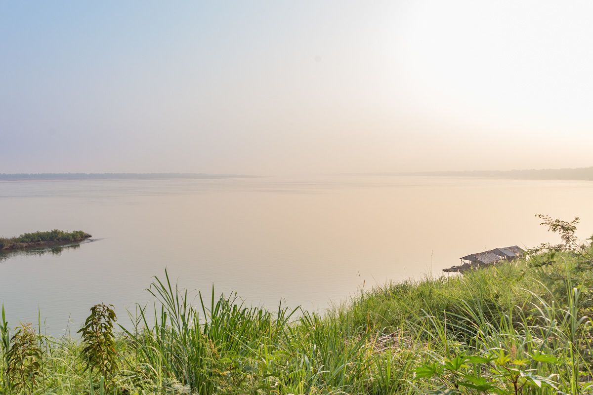 Una vista tranquila de un lago con una pequeña isla y una casa a lo lejos.