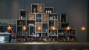 Un espace bar doté de plusieurs étagères remplies de bouteilles, d’un comptoir et de tabourets de bar.