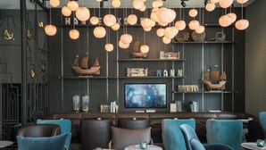 Un espace bar moderne avec des sièges en cuir, des luminaires suspendus et un grand écran de télévision.