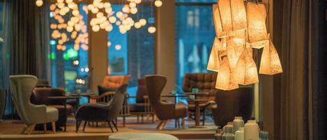 A modern interior with a dining area, hanging lights, and a view of the city at night.