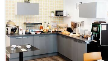 Una cocina moderna con armarios grises, un microondas, una cafetera y varios alimentos sobre la encimera.
