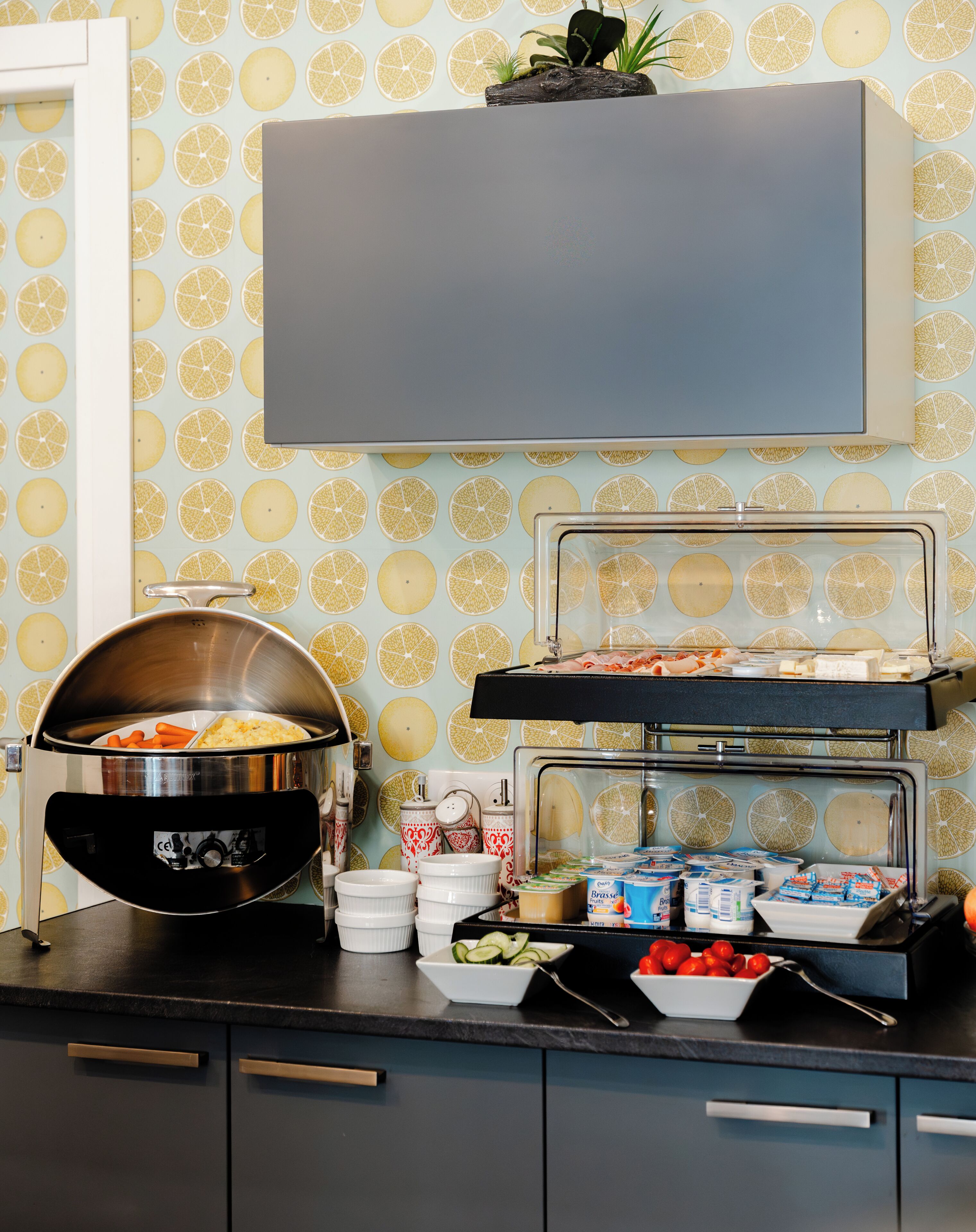 Montaje de bufé con diversas opciones de comida, incluyendo una olla tapada, tazones y una bandeja con alimentos.