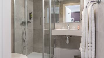 A modern bathroom with a glass-enclosed shower, a white sink, and a mirror above it.