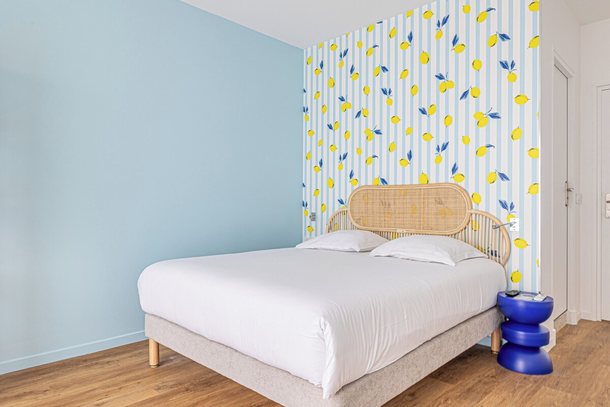 Un dormitorio con una cama, una pared con diseño a rayas y una puerta.
