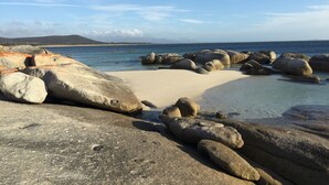 Une plage rocheuse parsemée de gros blocs de pierre, offrant une vue dégagée sur la mer.