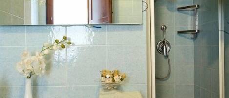A bathroom with a sink, mirror, shower, and a towel rack.