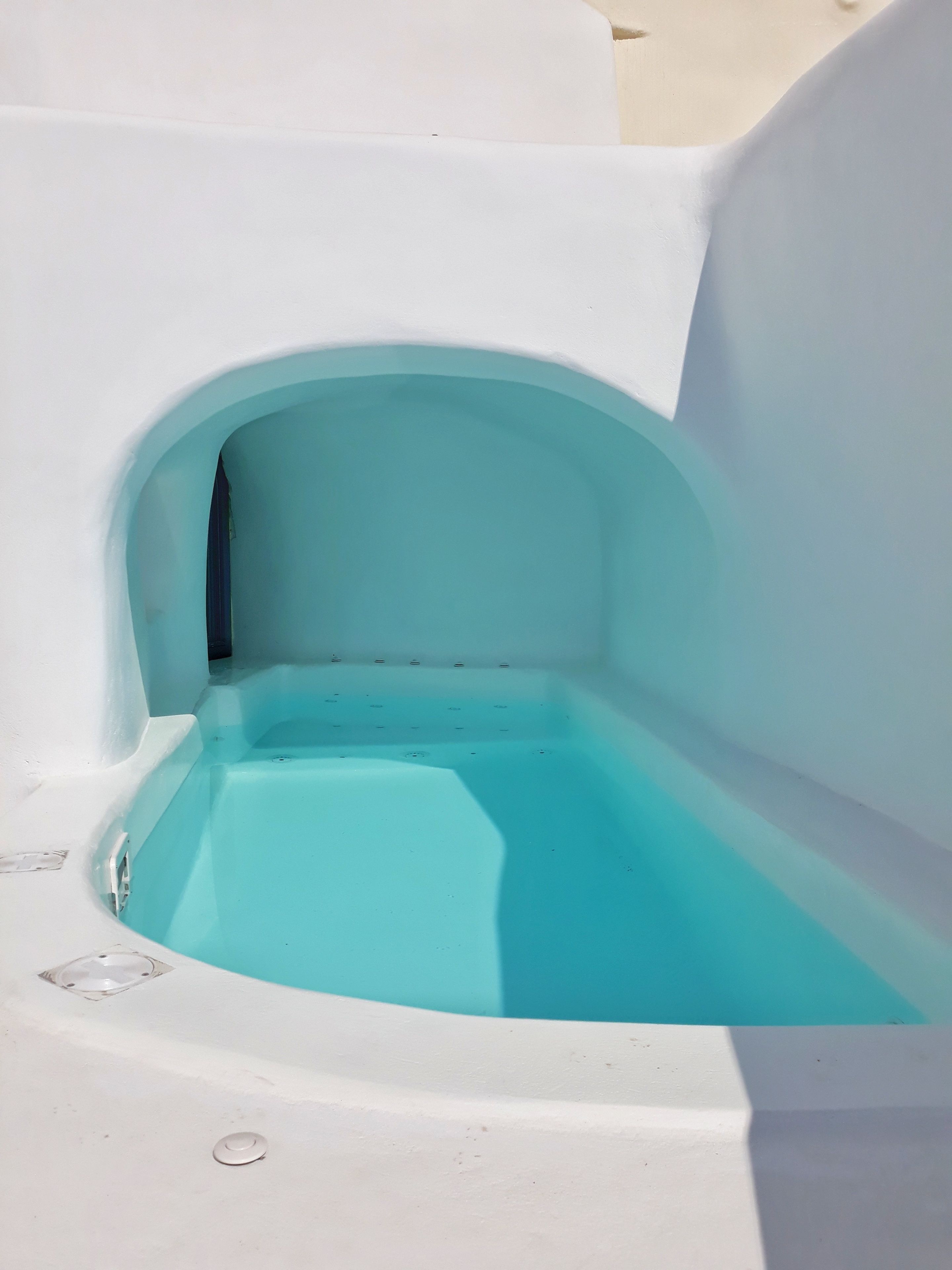 A white bathtub with a turquoise interior, a drain, and a small circular vent.