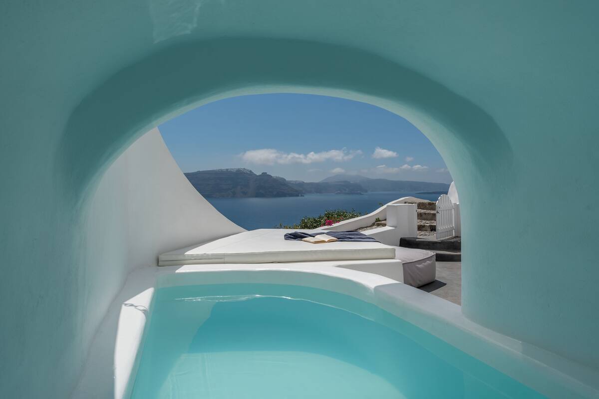 Un área de piscina moderna y minimalista, con vista despejada al mar y a islas distantes.