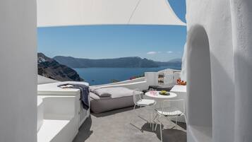 Un área de estar moderna al aire libre con vista al mar y a las montañas.