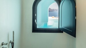 Een badkamer met een douche, een raam met uitzicht op zee, en een marmeren vloer.