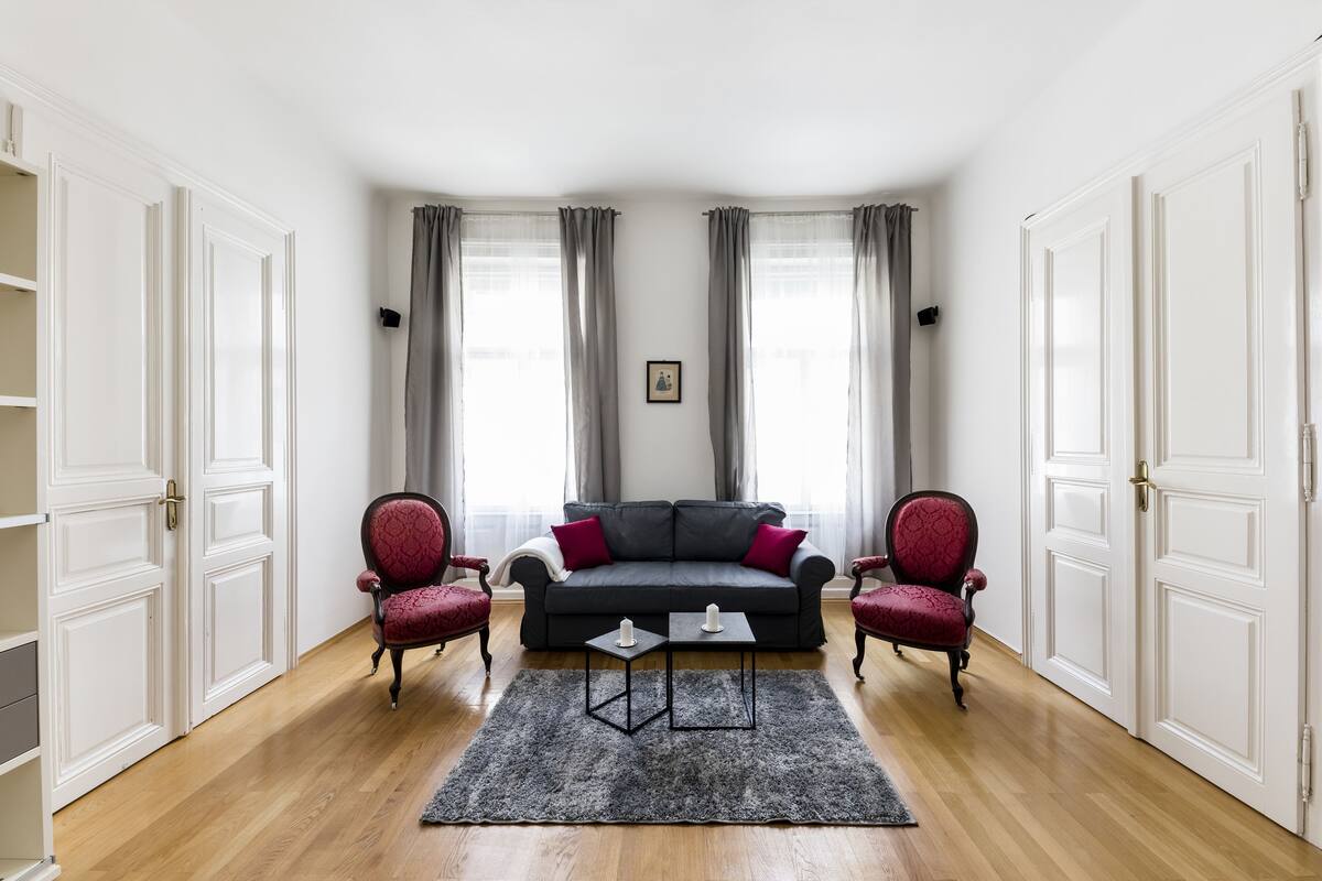 A living room with a dark sofa, two red armchairs, a coffee table, and a rug.