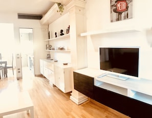 A modern living room with a flat-screen TV, white cabinetry, and a fireplace.
