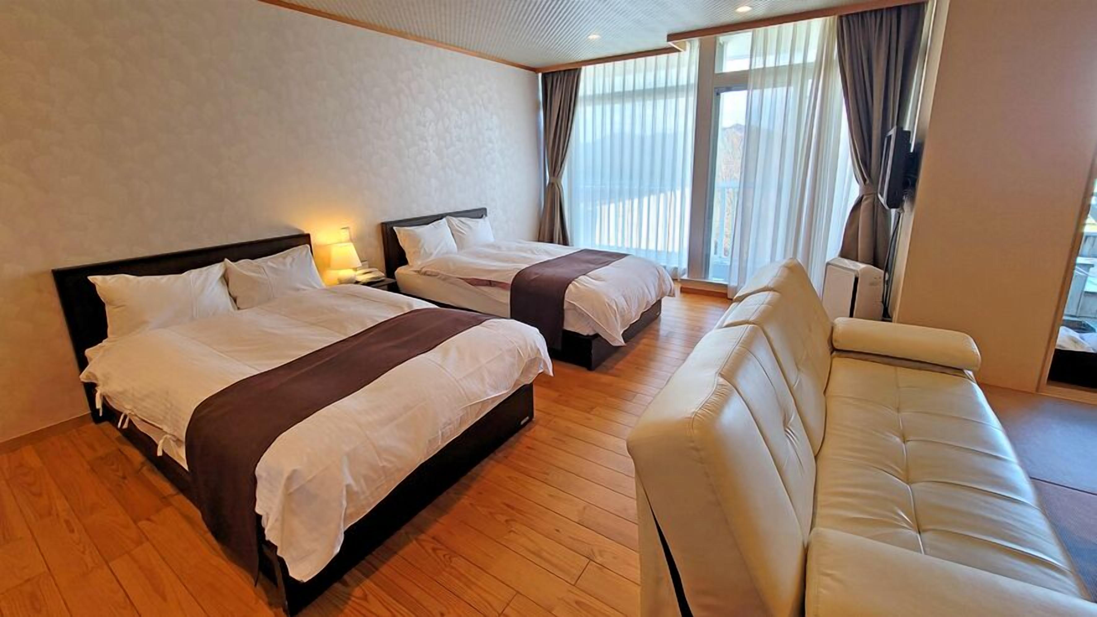 Une chambre d’hôtel avec deux lits, un canapé et une télévision.