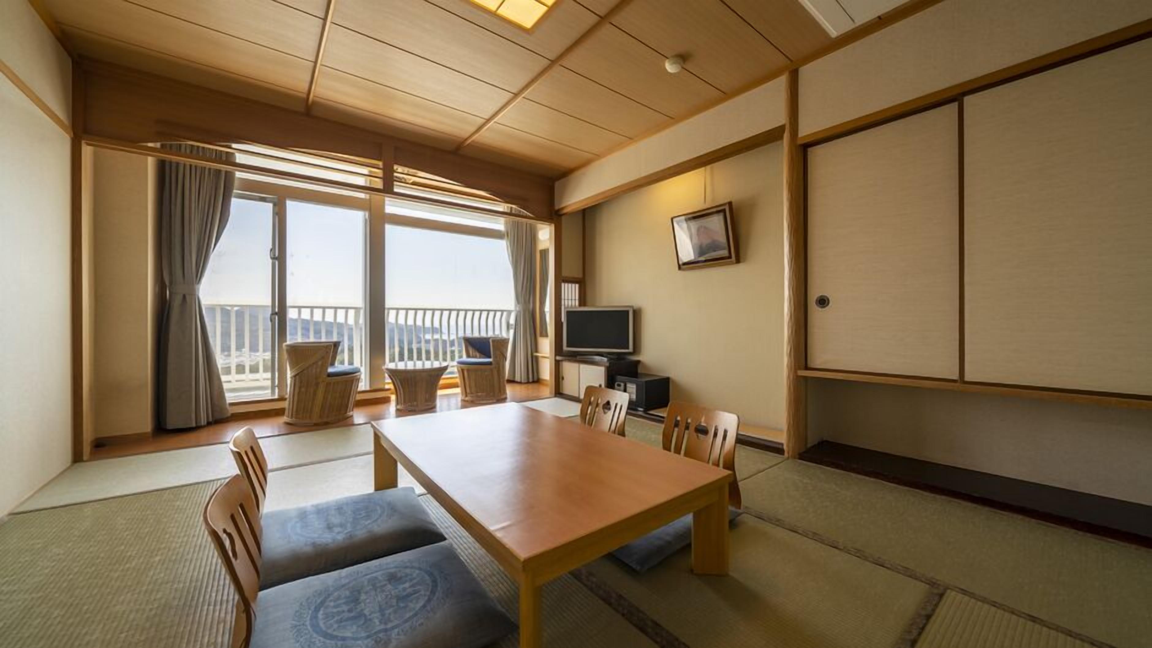 A traditional Japanese-style room with tatami flooring, a low wooden table, and a television on a cabinet.
