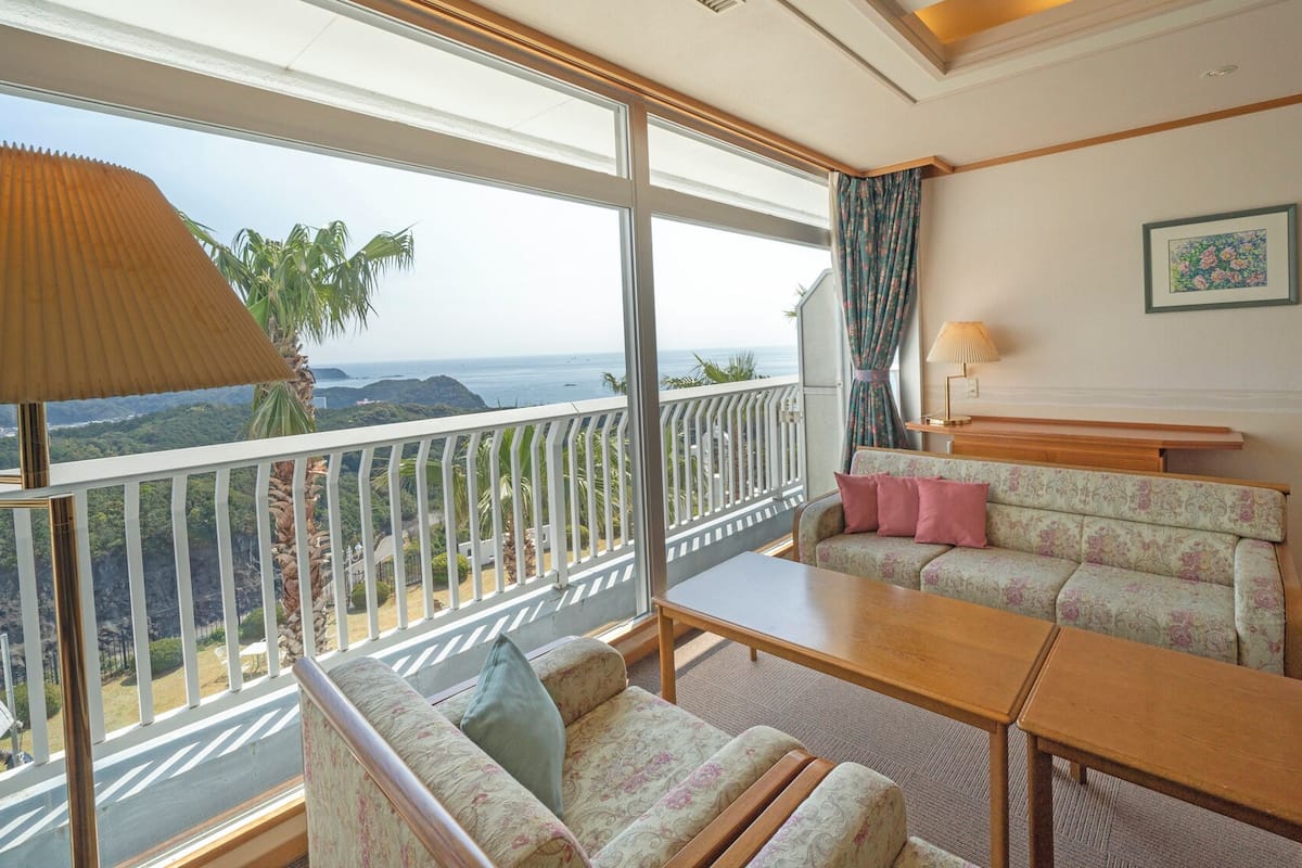 A room with a balcony, a sofa, a table, and a lamp.