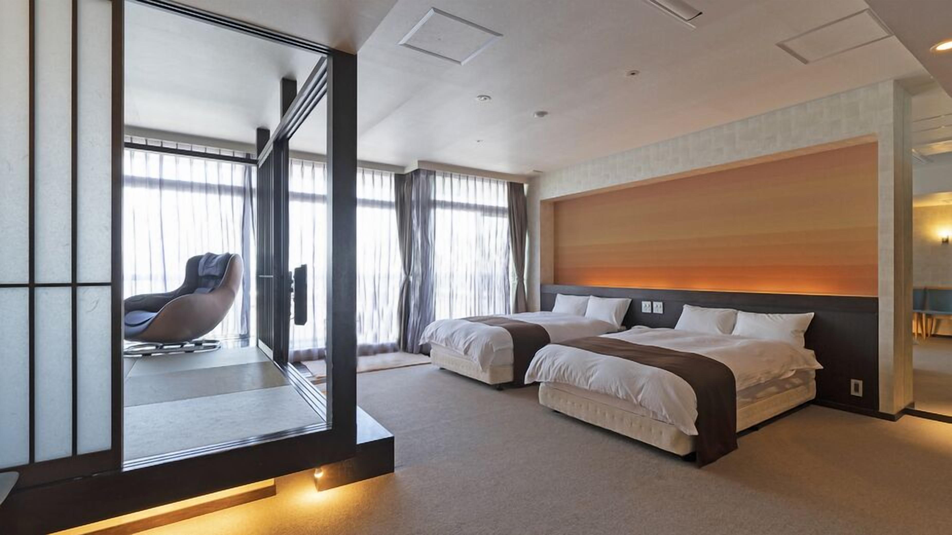 Une chambre d’hôtel moderne avec un grand lit, une chaise et une vue à travers une paroi en verre.