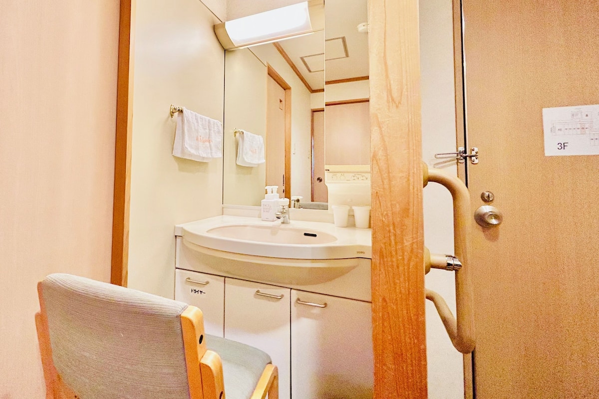 A bathroom with a sink, mirror, towel rack, and a chair.