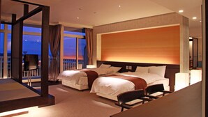 Habitación de hotel con dos camas, un escritorio y una silla. Cuenta con un ventanal grande con cortinas, y un diseño moderno.