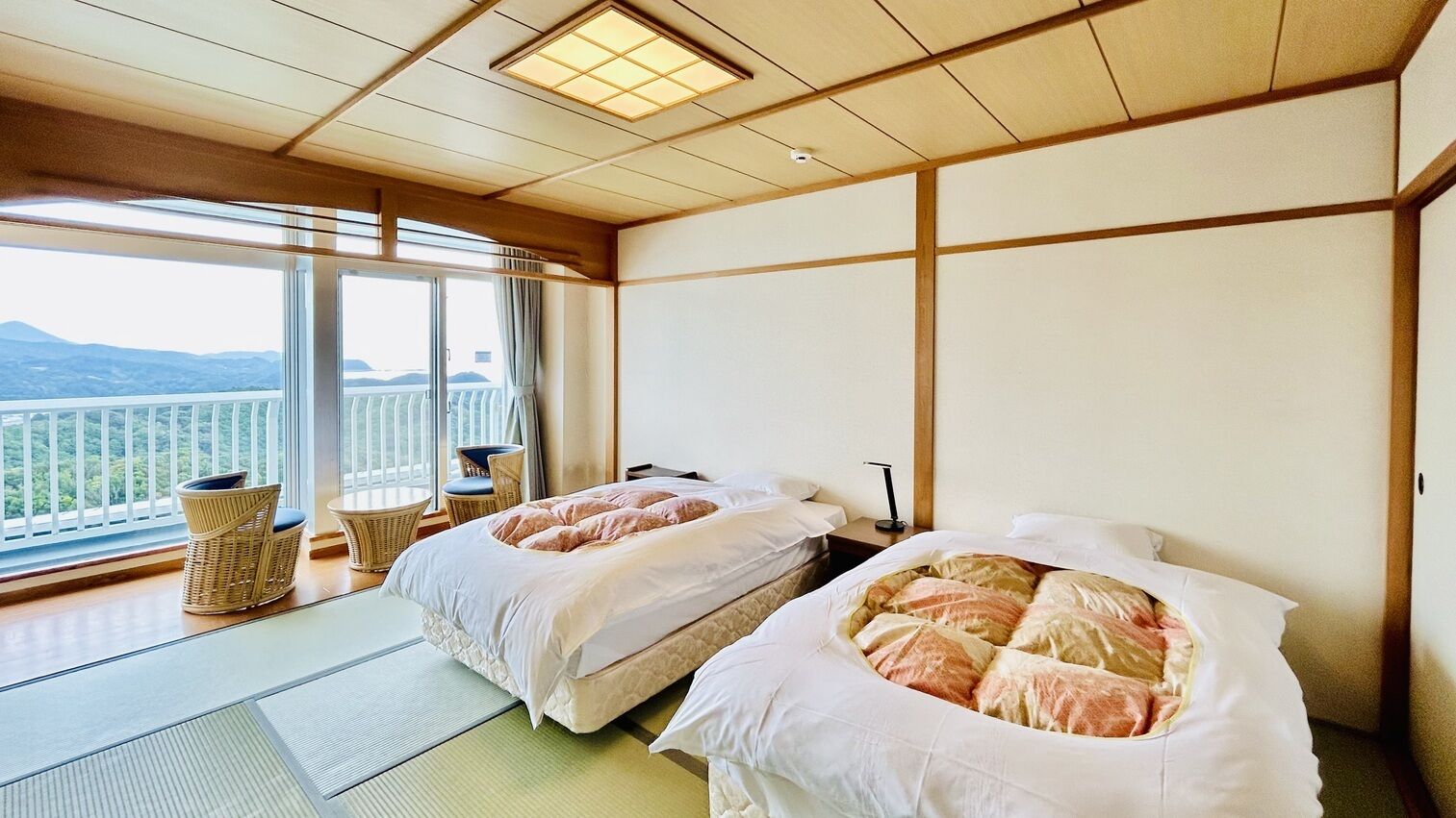 A hotel room with two beds, a balcony, and a view of the mountains.