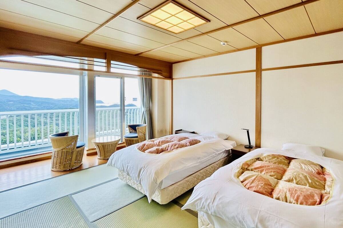 A hotel room with two beds, a balcony, and a view of the mountains.