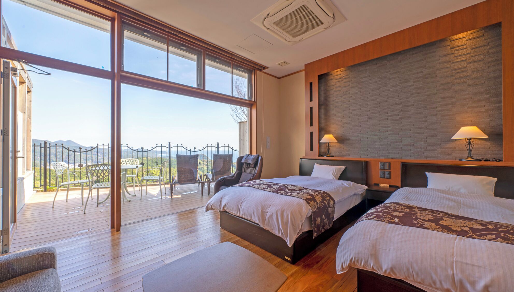 Une chambre avec deux lits, un balcon avec des chaises et une vue sur les montagnes.