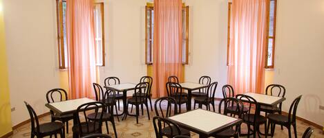 A dining area with multiple tables and chairs, arranged in a circular pattern around a central open space.