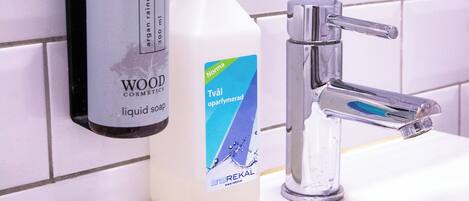 A bathroom sink with a soap dispenser and a bottle of liquid soap.