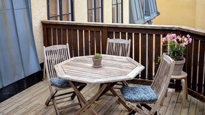 A wooden deck with a round table and chairs, a potted plant, and a lantern. - Adelsgatan Bed & Breakfast (Visby)
