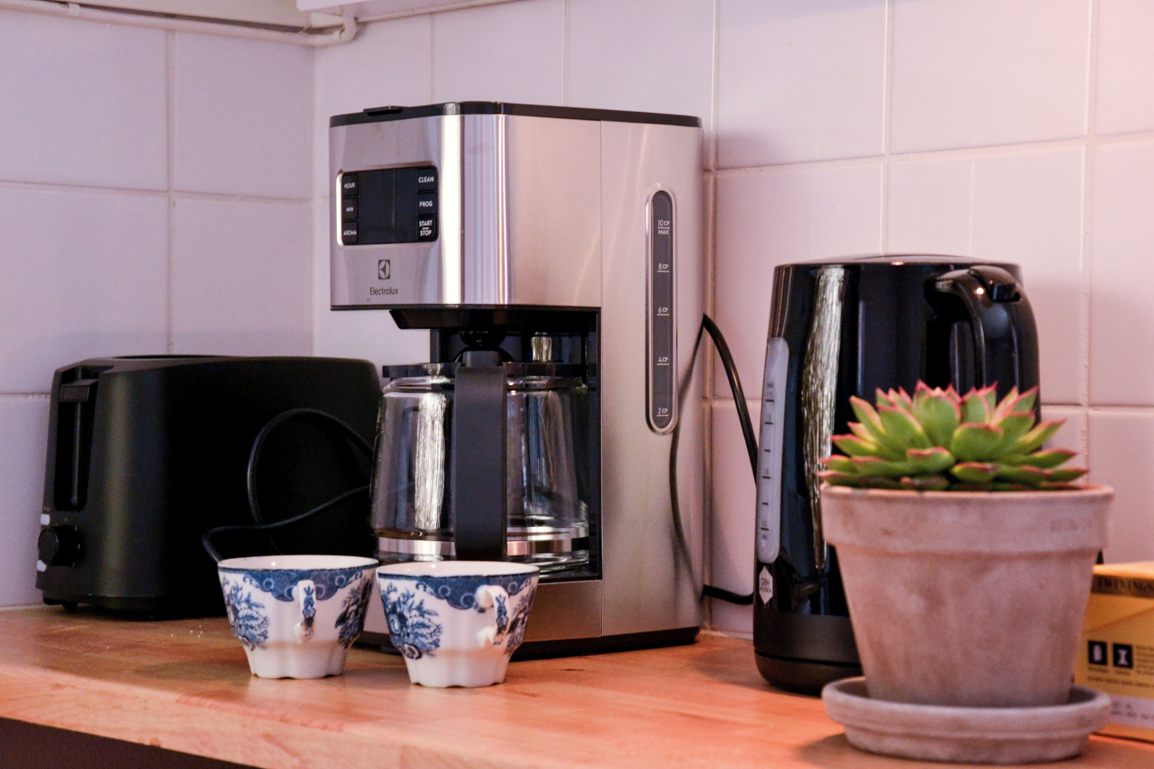 Eine Küche mit Kaffeemaschine, zwei Tassen und einem Blumentopf.