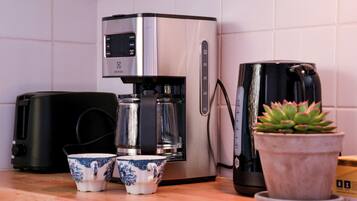 Eine Küche mit Kaffeemaschine, zwei Tassen und einem Blumentopf.