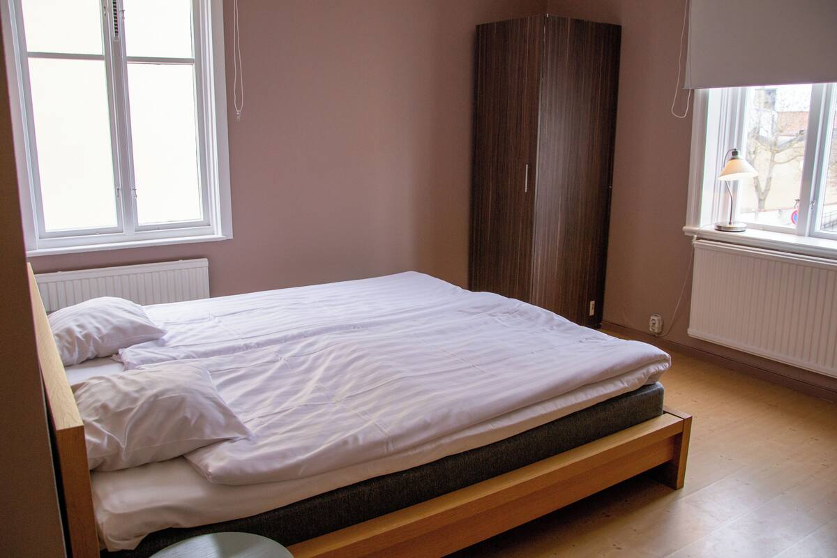 A bedroom with a bed, a wardrobe, and a window.