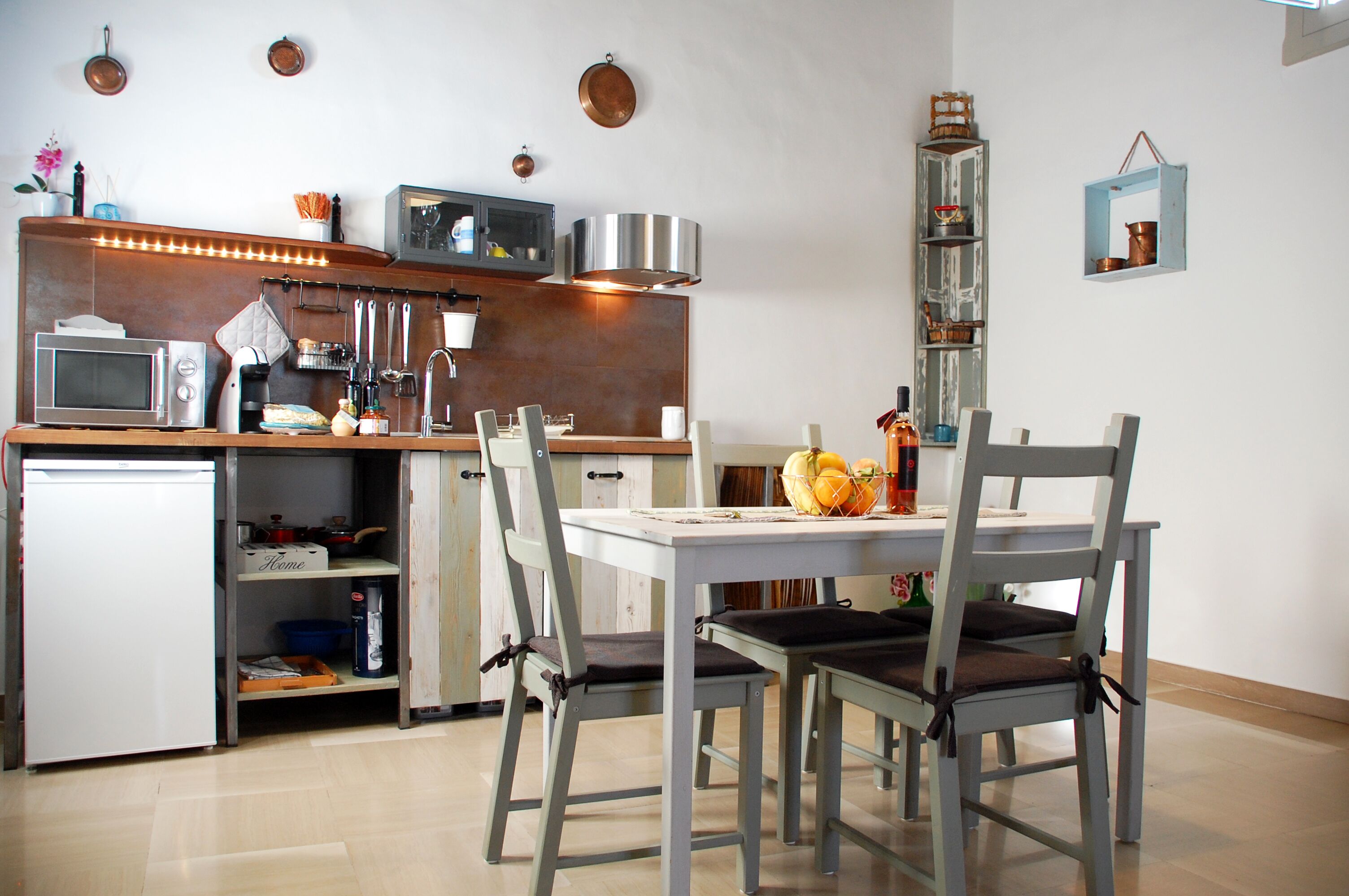 A compact kitchen with a microwave, sink, and a dining area with chairs and a table.