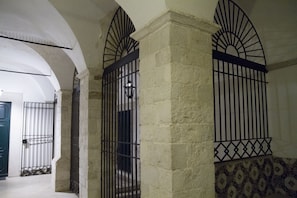 Un pasillo con paredes de piedra, rejas de metal y baldosas estampadas.