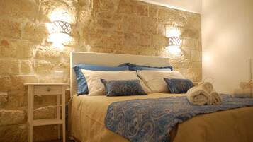 A bed with a headboard, a bedside table, and a wall with stone texture.