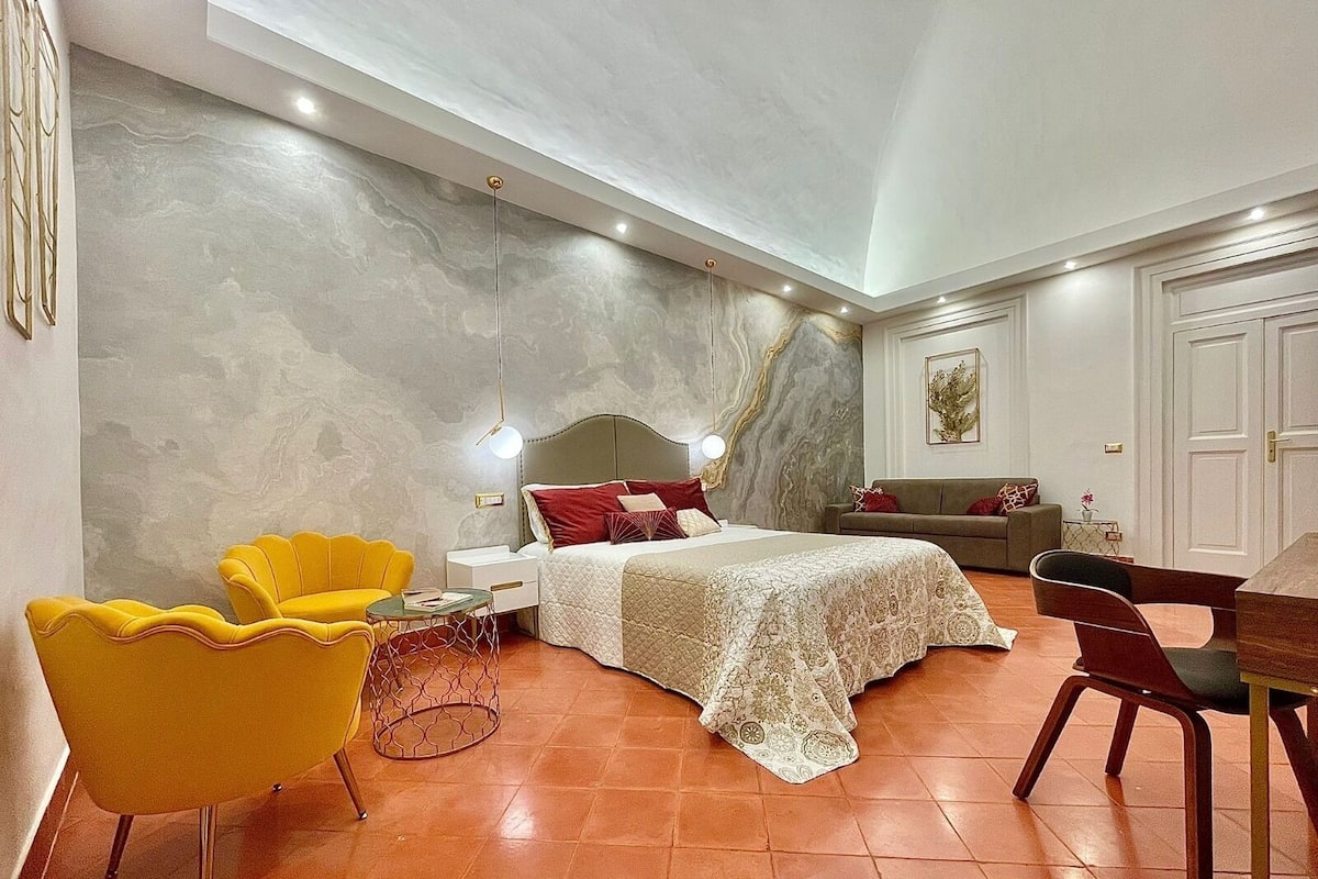Une chambre à coucher comprenant un lit, une table de chevet, une chaise, un canapé et une table à manger.