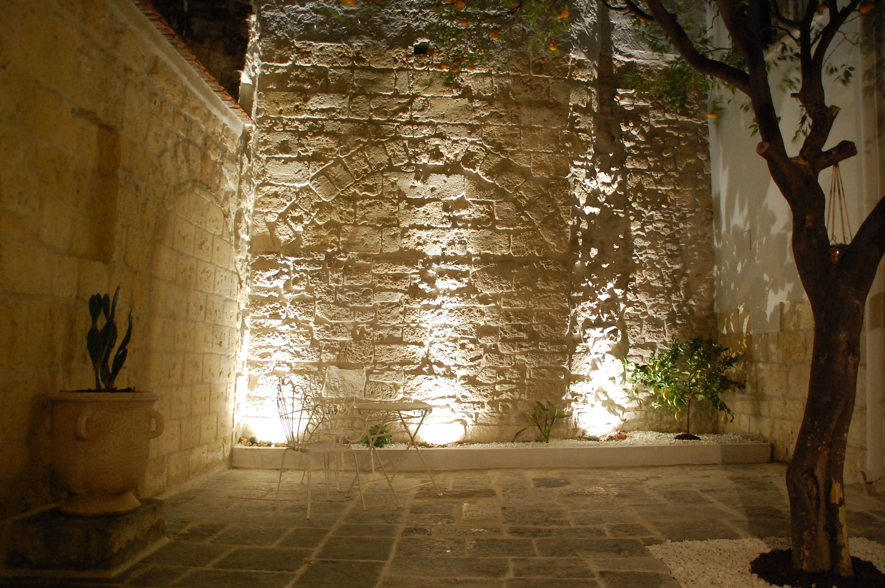 Un mur de pierre avec un petit espace aménagé pour s’asseoir et un arbre dans une cour.