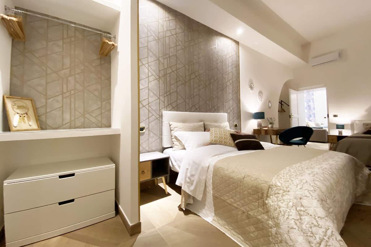 Une chambre moderne avec un grand lit, une table de chevet, une chaise et une armoire.