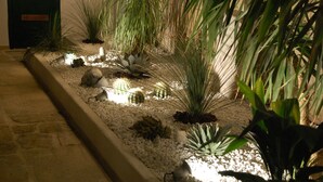 Een verzorgde tuin met verschillende planten en decoratieve stenen, begrensd door een pad van natuursteen.