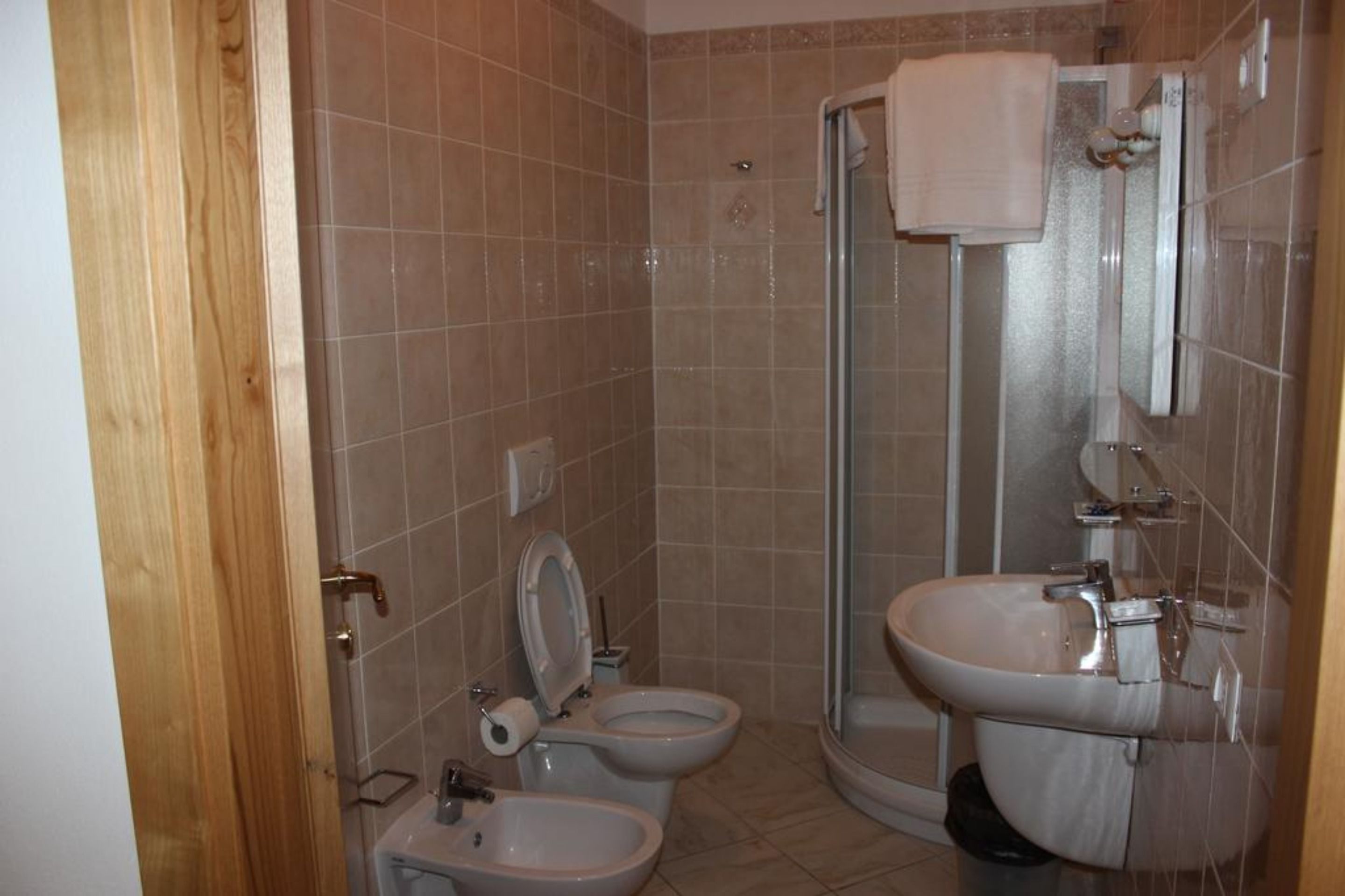 A bathroom with a toilet, bidet, sink, and glass shower enclosure.