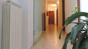 A hallway with a radiator, a plant, and a door at the end. - Albergo Ristorante La Bocca di Bacco (Abbadia San Salvatore)