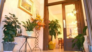 A hotel entrance with a wooden door, a small table with a vase of flowers, and potted plants on either side. - Albergo Ristorante La Bocca di Bacco (Abbadia San Salvatore)