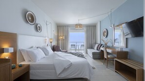 A modern hotel room with a large bed, a desk, a TV, and a balcony with a view.