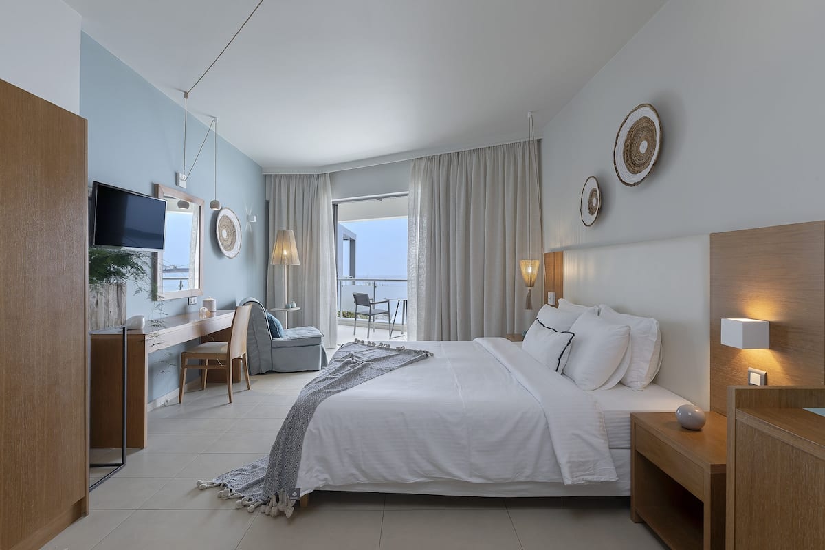 Una habitación de hotel moderna con cama, escritorio, silla y un balcón con vistas.