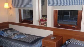 Une chambre avec un lit, une petite table de chevet en bois et une fenêtre donnant sur l’extérieur.