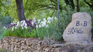 A stone wall with a sign reading "B&B Le Vallee" surrounded by white and purple flowers. - Bed & Breakfast La Valle (Talamello)
