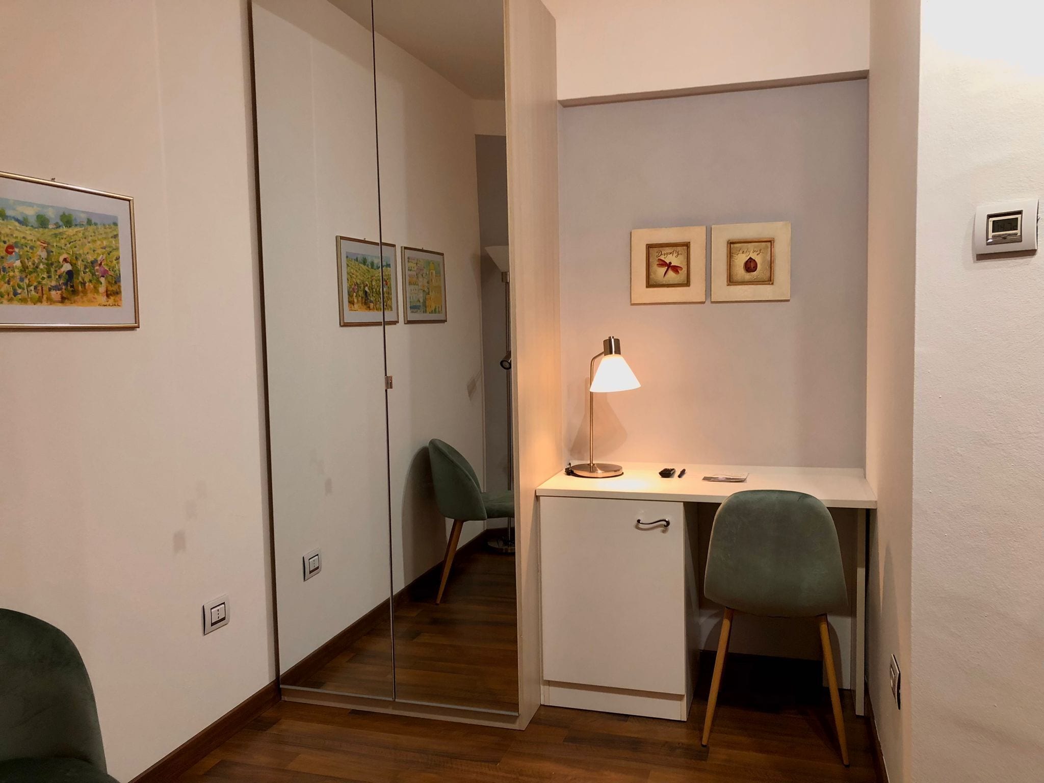 Une chambre moderne équipée d’un bureau, de deux chaises, d’un miroir et de tableaux encadrés accrochés au mur.