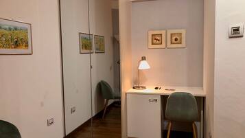 Une chambre moderne équipée d’un bureau, de deux chaises, d’un miroir et de tableaux encadrés accrochés au mur.