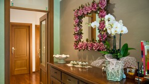 A wooden dresser with a mirror, a vase with white orchids, and a decorative item with lace. - Bed & Breakfast La Valle (Talamello)