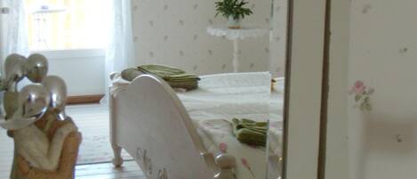 A bedroom with a bed, a bedside table with a plant, and a mirror.